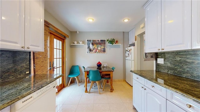 kitchen with dark stone countertops, decorative backsplash, white cabinets, and white appliances