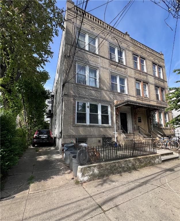 townhome / multi-family property with concrete driveway, brick siding, and a fenced front yard