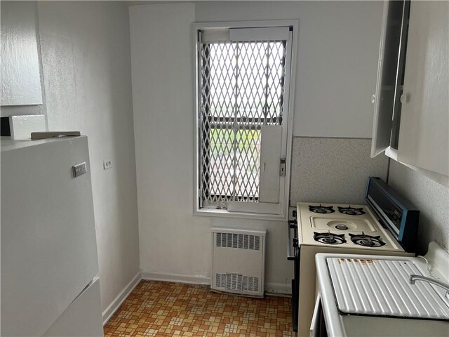 kitchen with electric range oven, radiator, and white fridge