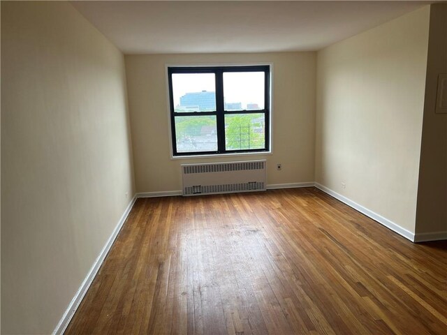 empty room with radiator and hardwood / wood-style floors