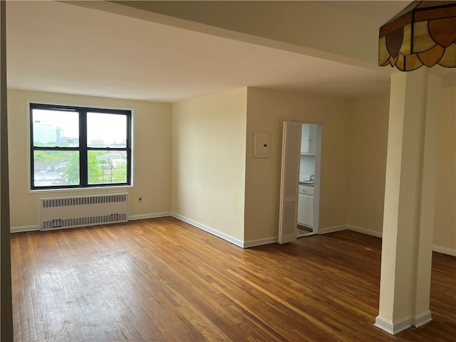 unfurnished room with hardwood / wood-style flooring and radiator heating unit