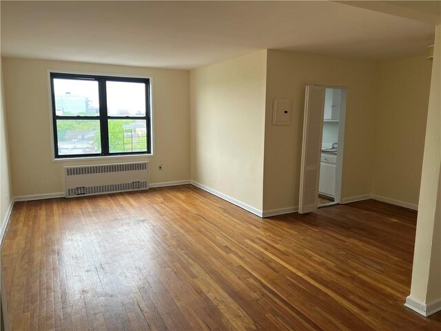 empty room featuring hardwood / wood-style floors and radiator heating unit