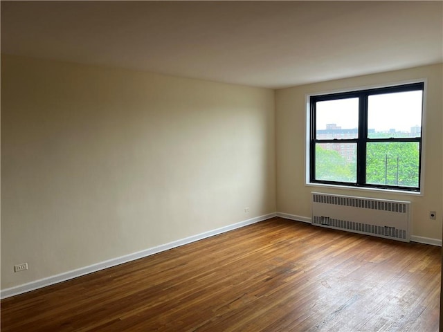 spare room with radiator heating unit and wood-type flooring