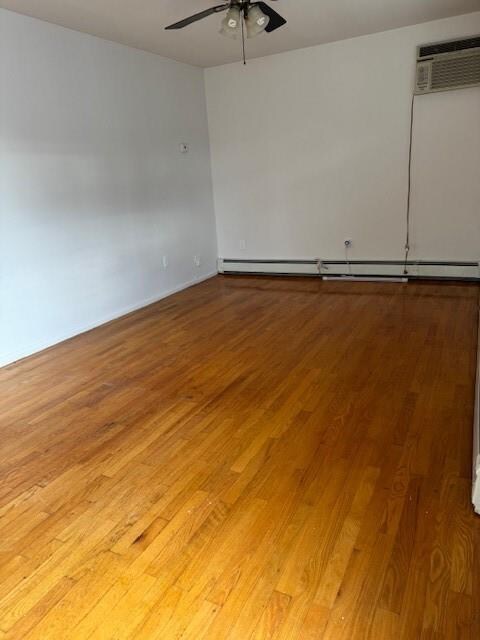 unfurnished room with a baseboard heating unit, dark wood-type flooring, and ceiling fan