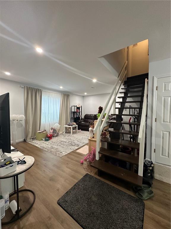 living room with stairs, recessed lighting, and wood finished floors