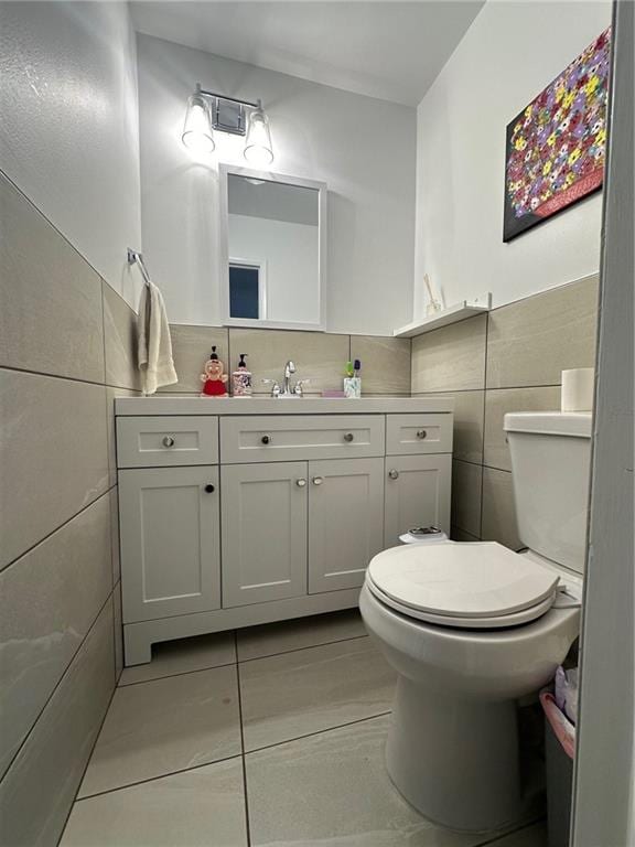 half bathroom with vanity, tile walls, and toilet