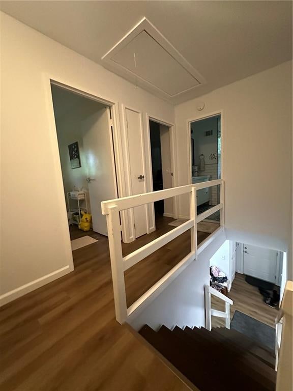 hallway featuring attic access, wood finished floors, an upstairs landing, and baseboards