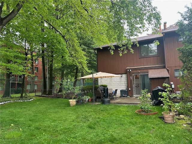 rear view of house featuring a yard, a patio, and fence