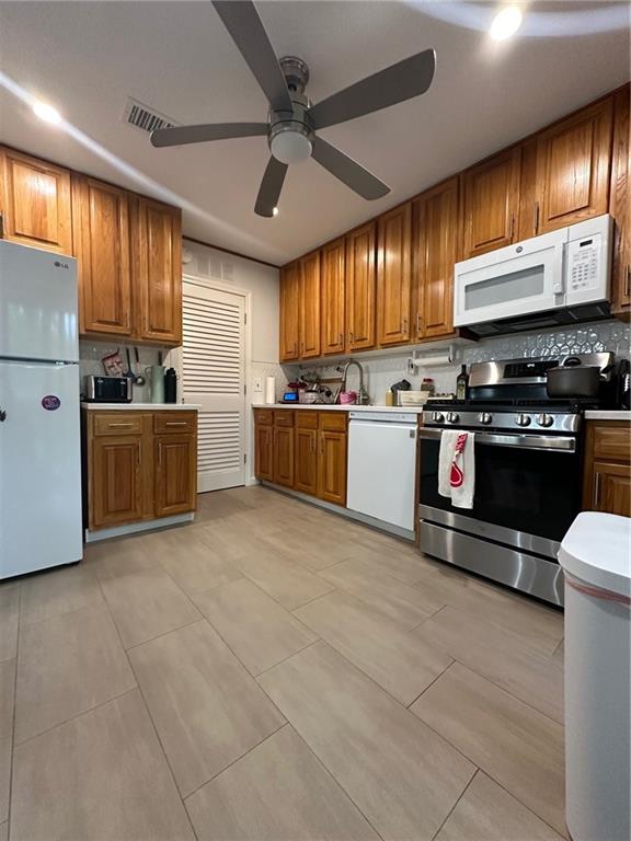 kitchen with white appliances, light tile patterned flooring, sink, backsplash, and ceiling fan