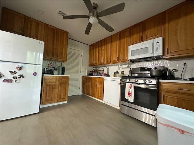 kitchen featuring white appliances, light countertops, visible vents, and brown cabinets