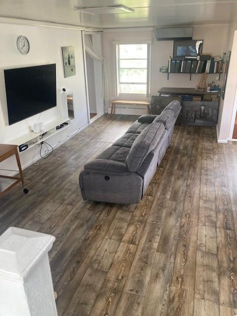 living room with dark hardwood / wood-style flooring and a wall unit AC