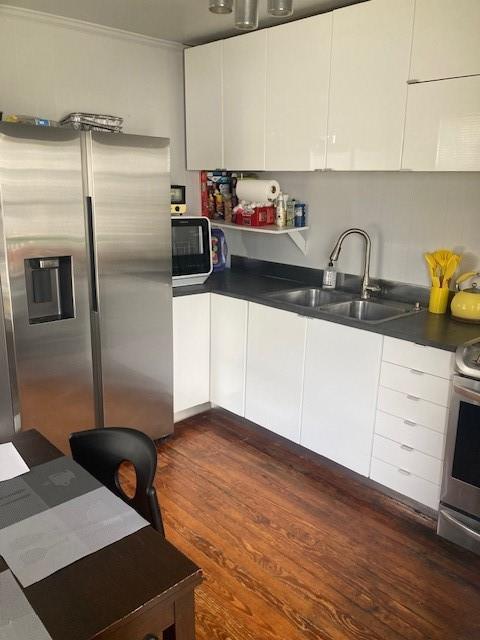 kitchen featuring white cabinetry, appliances with stainless steel finishes, dark wood-type flooring, and sink