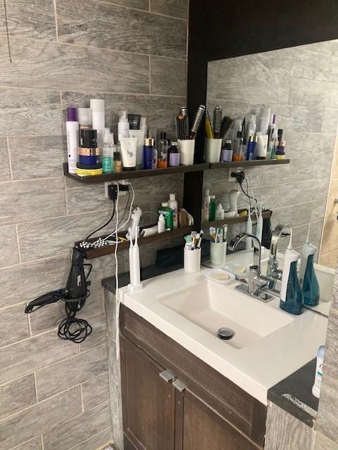 bar featuring sink, dark brown cabinets, and tile walls