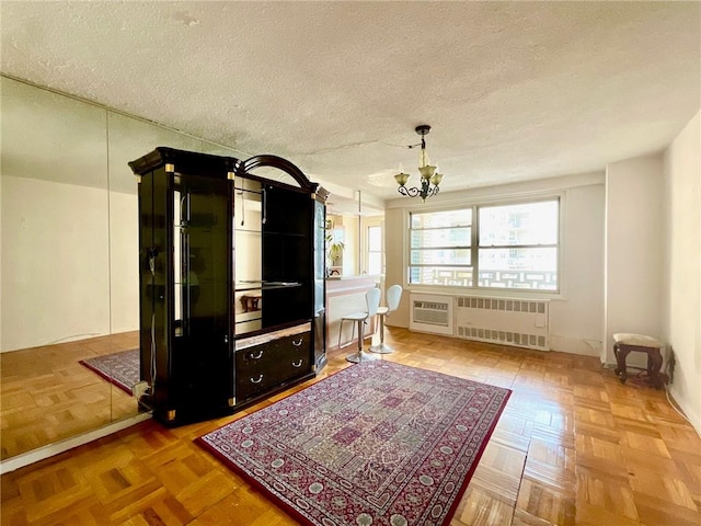 miscellaneous room featuring radiator, parquet flooring, a textured ceiling, and a chandelier