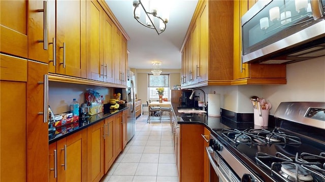 kitchen featuring sink, light tile patterned floors, stainless steel appliances, and a notable chandelier