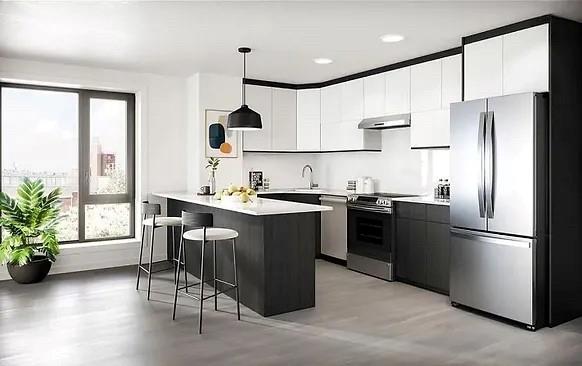 kitchen with a healthy amount of sunlight, a kitchen bar, hanging light fixtures, and appliances with stainless steel finishes