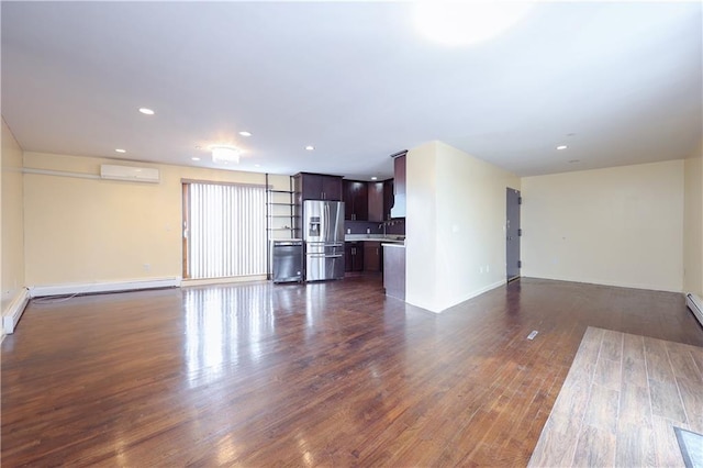 unfurnished living room featuring a wall mounted AC, sink, and dark wood-type flooring