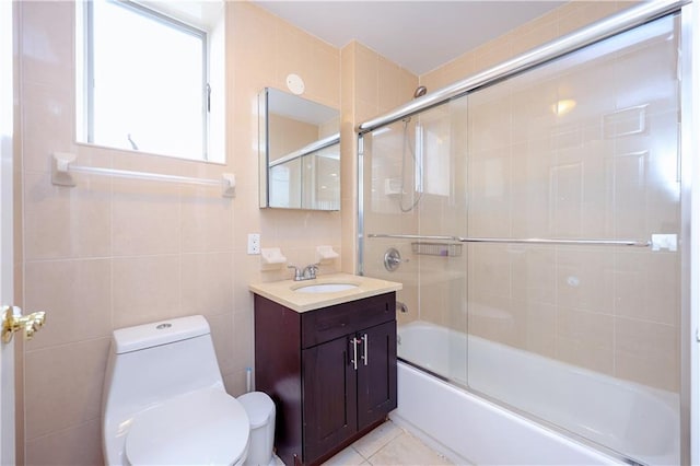 full bathroom with combined bath / shower with glass door, vanity, toilet, and tile walls