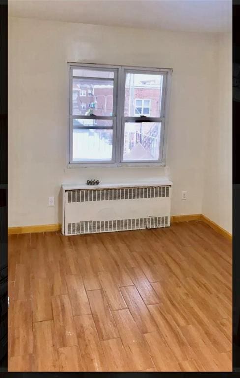 empty room with radiator and hardwood / wood-style floors