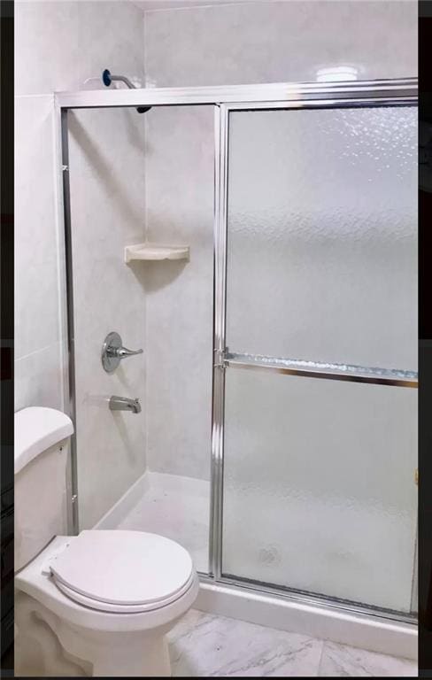 bathroom featuring toilet and a shower with shower door