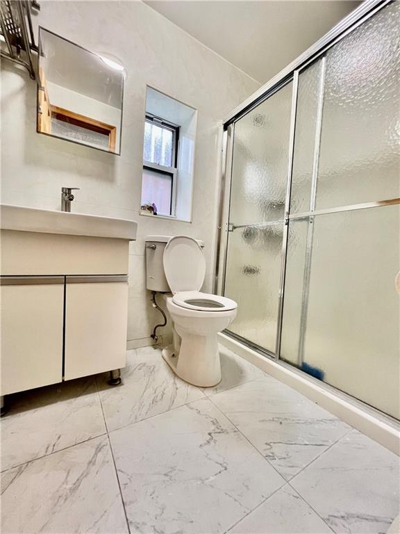 bathroom with vanity, toilet, and a shower with shower door