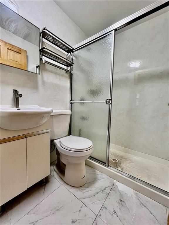 bathroom featuring vanity, a shower with shower door, and toilet