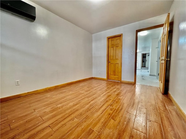 unfurnished room with light hardwood / wood-style flooring and a wall mounted air conditioner