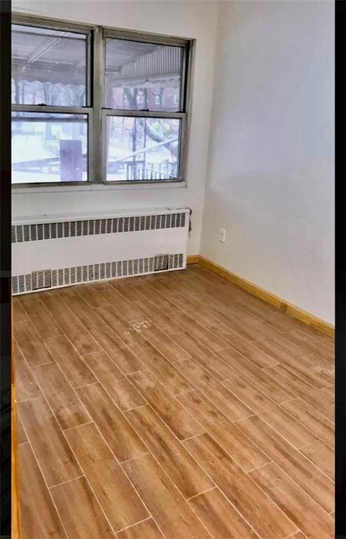 spare room with radiator heating unit and wood-type flooring