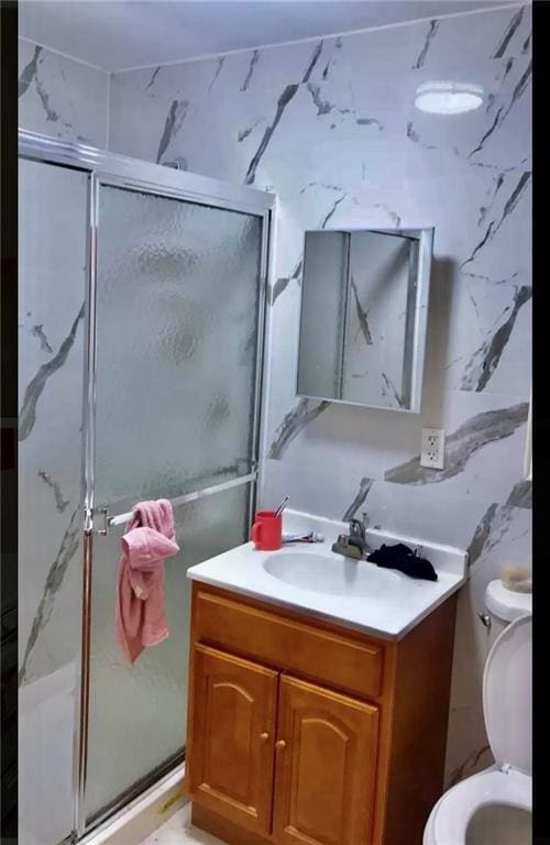 bathroom featuring vanity, a shower with shower door, and toilet