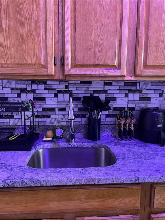 room details with tasteful backsplash, sink, and light stone counters