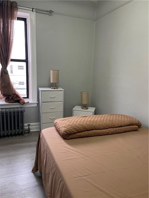 bedroom with wood-type flooring and radiator