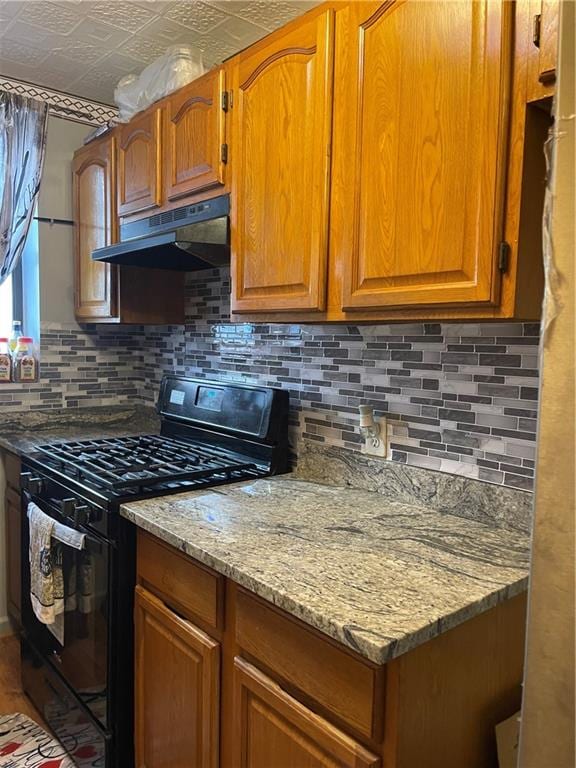 kitchen featuring light stone countertops, gas stove, and tasteful backsplash