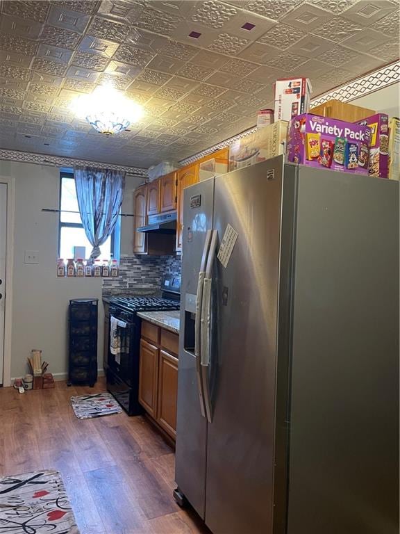 kitchen with black range, backsplash, stainless steel fridge, and dark hardwood / wood-style flooring