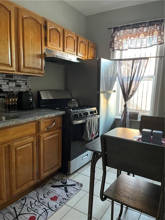 kitchen featuring light tile patterned floors, decorative backsplash, stainless steel gas stove, and sink