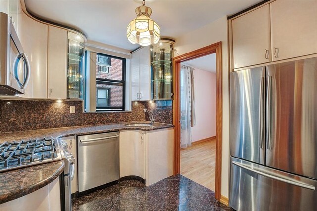 kitchen with dark stone countertops, sink, decorative light fixtures, and appliances with stainless steel finishes