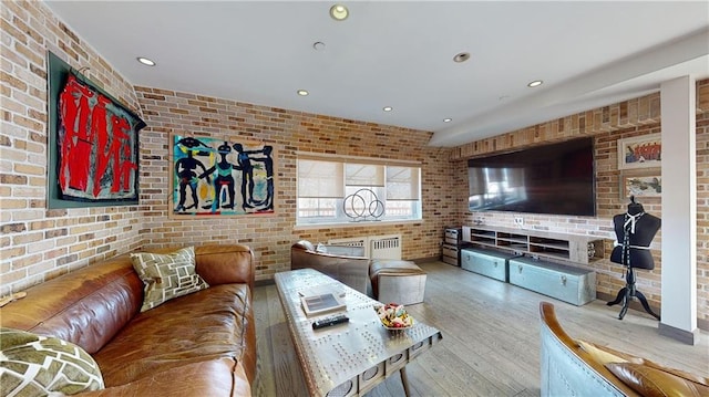 living room featuring brick wall and light wood-type flooring