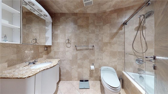 full bathroom featuring toilet, tiled shower / bath, tile walls, vanity, and tile patterned flooring