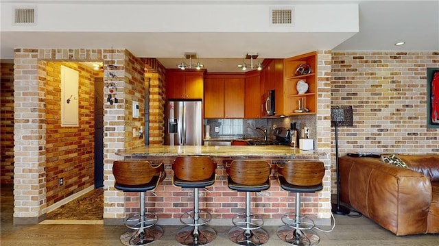 kitchen featuring hardwood / wood-style flooring, appliances with stainless steel finishes, a kitchen bar, and kitchen peninsula