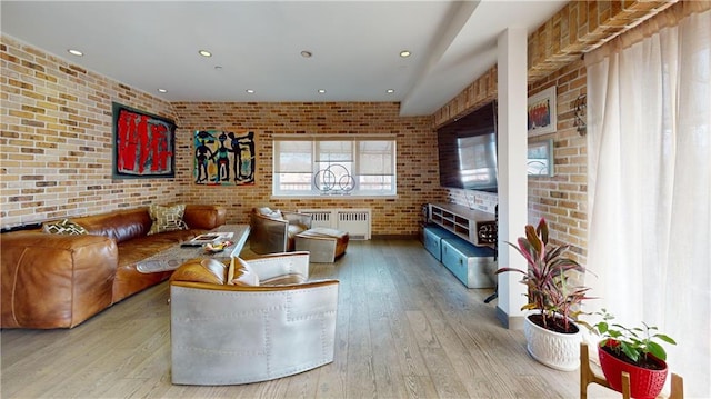 living room with brick wall, radiator, and light hardwood / wood-style floors