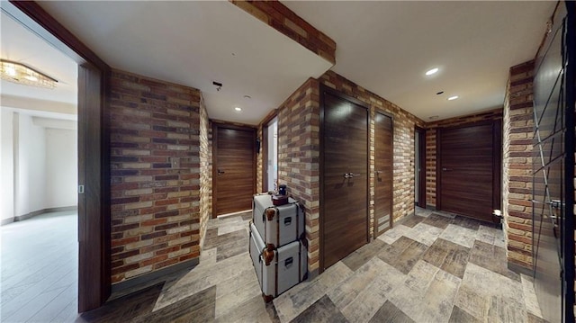 corridor with brick wall and light hardwood / wood-style flooring