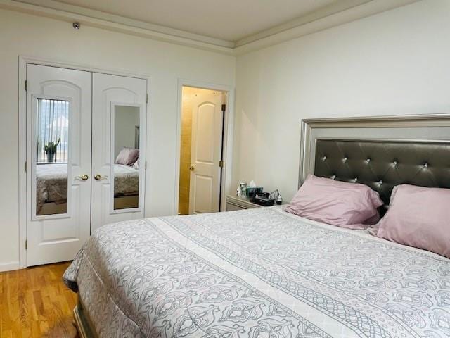 bedroom with a closet, hardwood / wood-style flooring, ornamental molding, and french doors