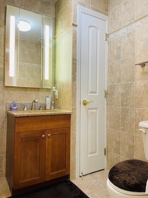 bathroom featuring tile patterned floors, toilet, tile walls, and vanity