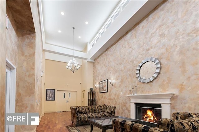 living room with an inviting chandelier, hardwood / wood-style floors, and a high ceiling