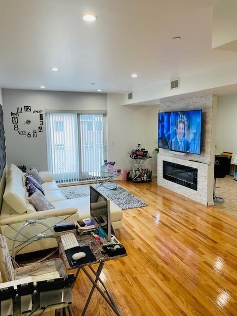 living room with wood-type flooring and a large fireplace