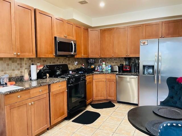 kitchen with stainless steel appliances, sink, decorative backsplash, and dark stone counters