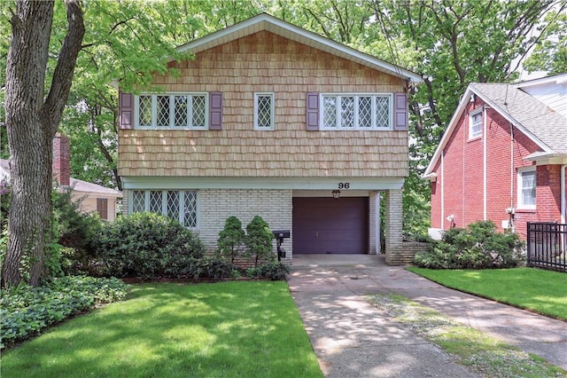 colonial inspired home with a garage, a front lawn, concrete driveway, and brick siding