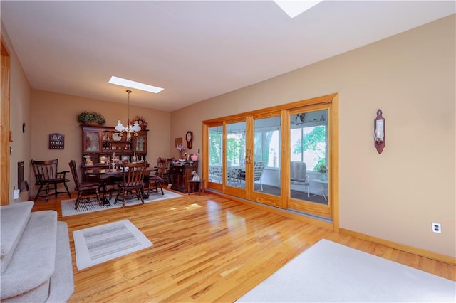 living room with wood finished floors, baseboards, french doors, and an inviting chandelier