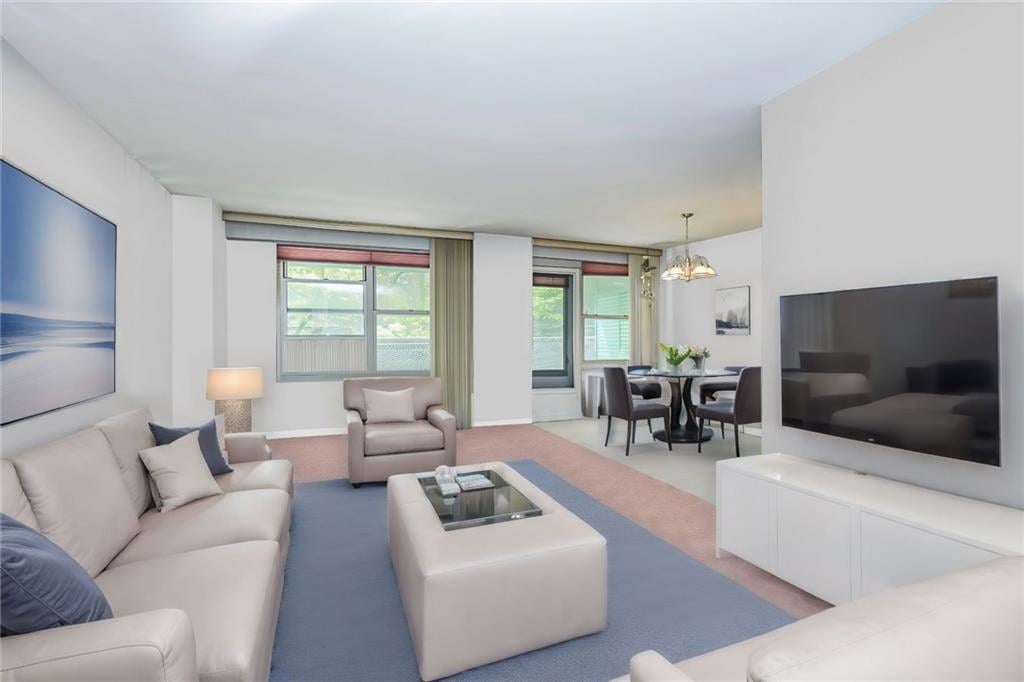 carpeted living room featuring an inviting chandelier