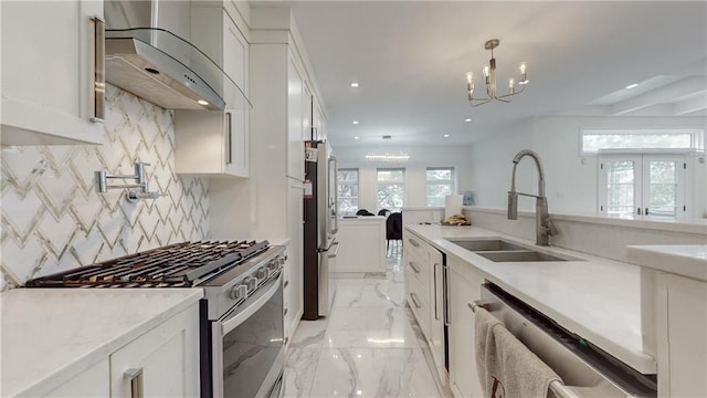 kitchen with appliances with stainless steel finishes, white cabinetry, wall chimney exhaust hood, french doors, and sink