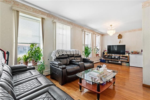 living room with a baseboard heating unit, baseboard heating, an inviting chandelier, and wood finished floors